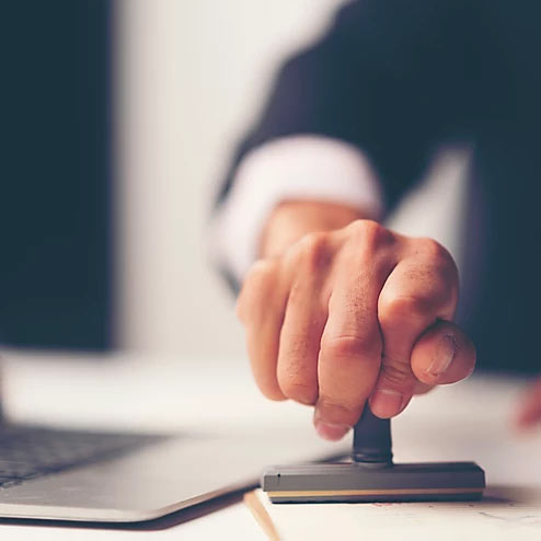 Photo d'une main qui tient un tampon appuyé sur une feuille de papier